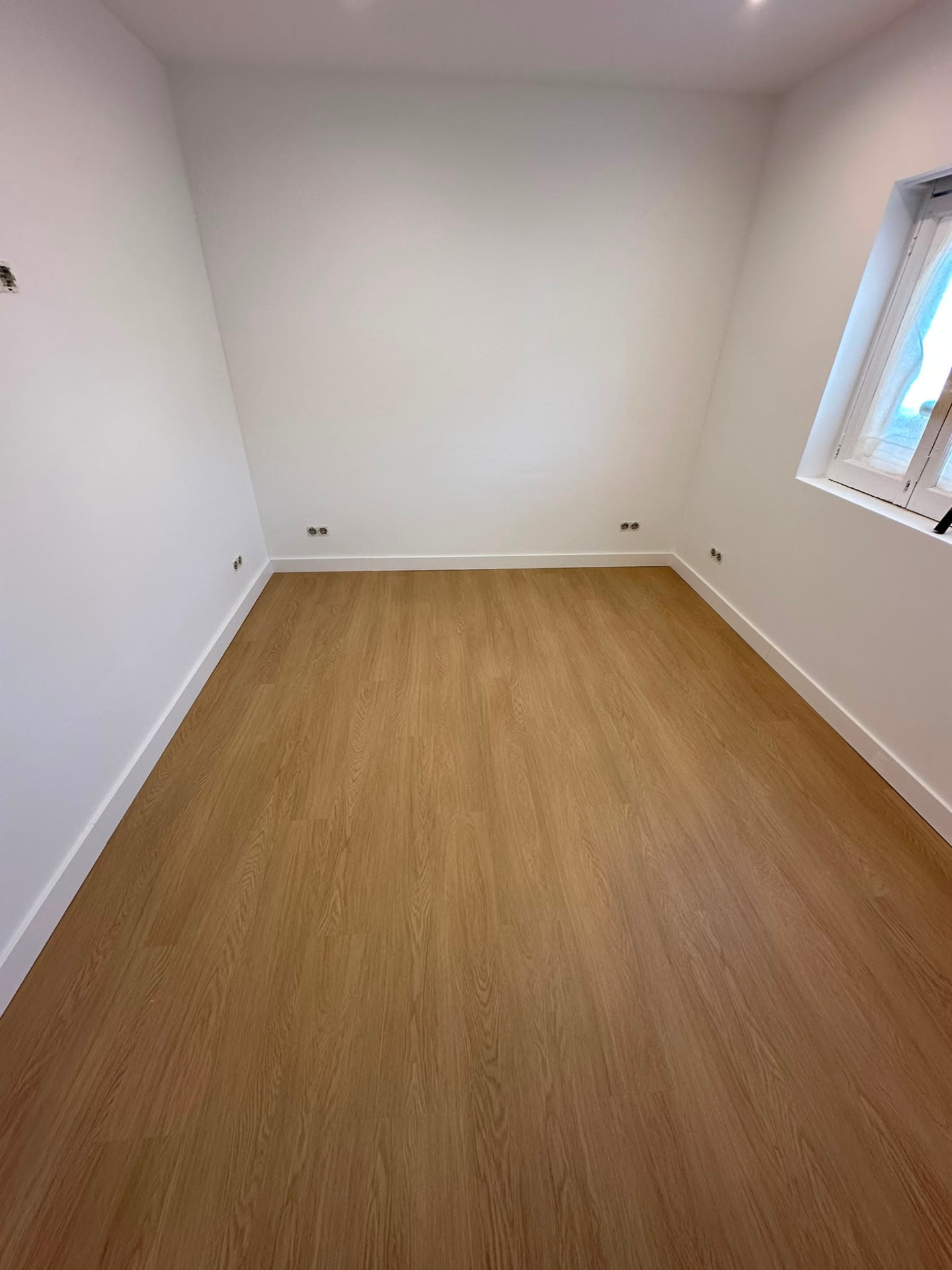 Quarto remodelado com pavimento vinílico e paredes pintadas de branco