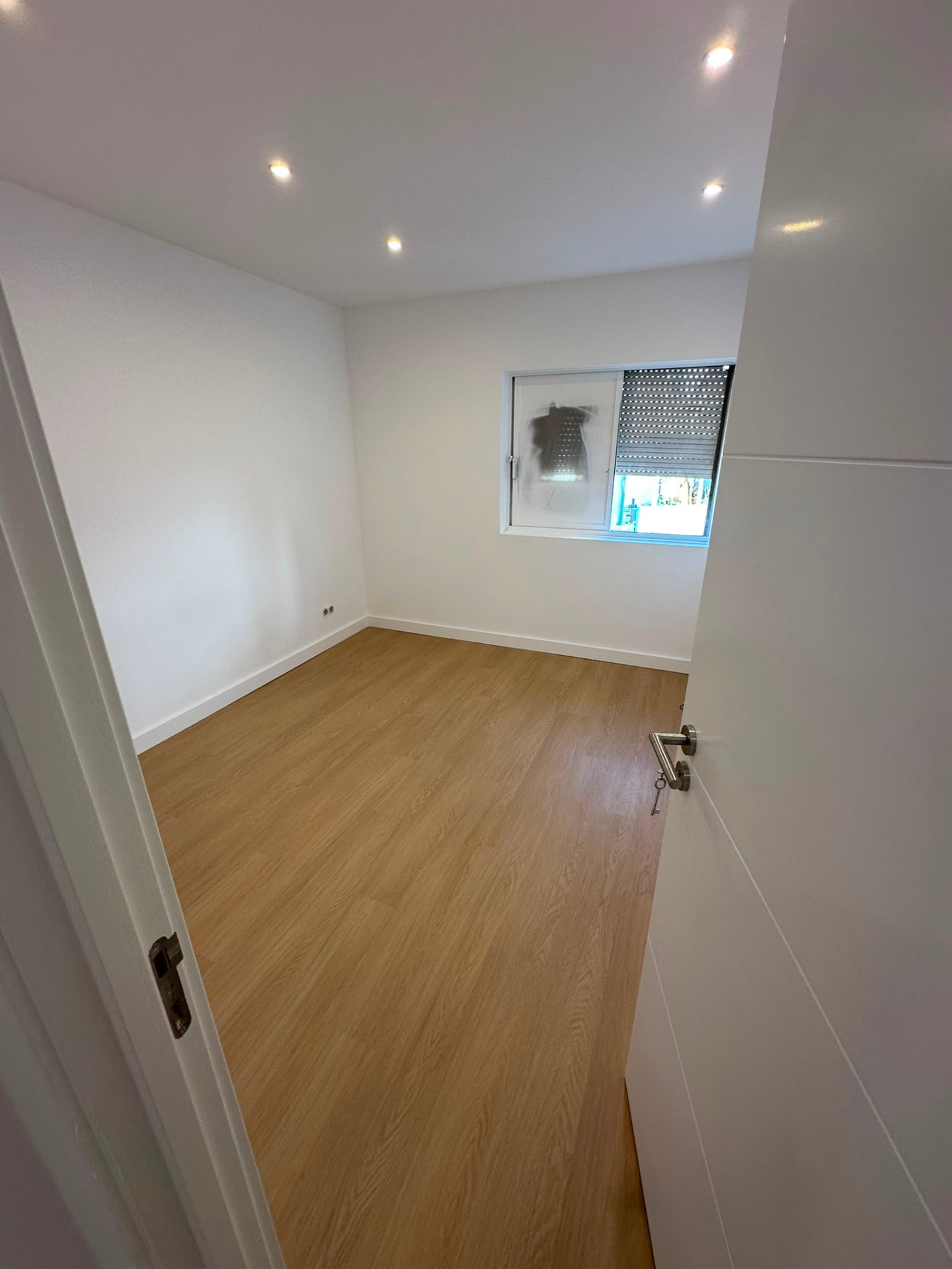 Quarto com focos embutidos no teto falso e pavimento novo em madeira