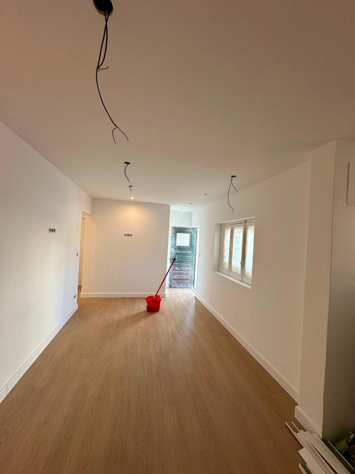 Sala ampla remodelada com pavimento em madeira e paredes acabadas