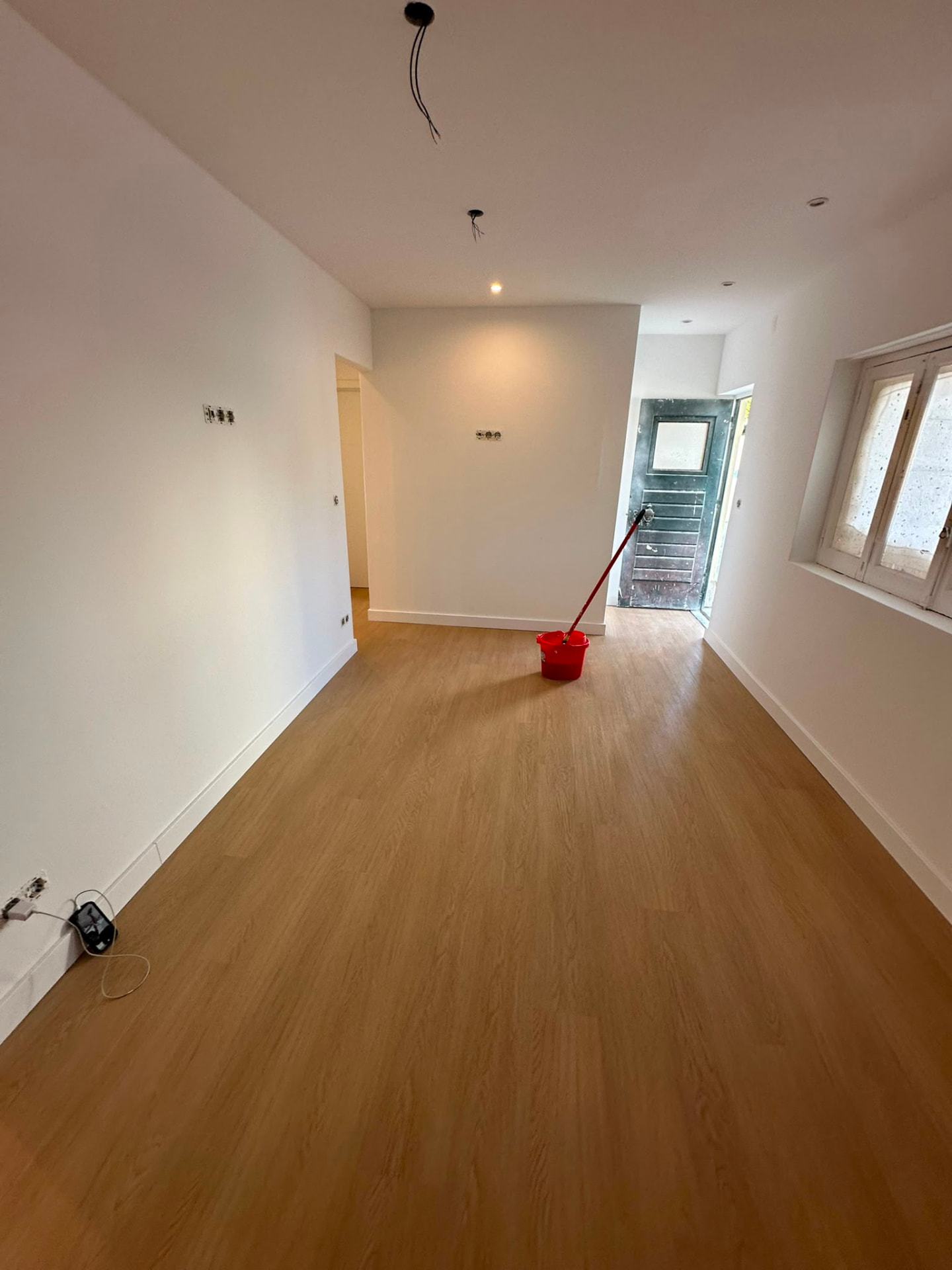 Sala ampla com pavimento novo em madeira e paredes pintadas de branco